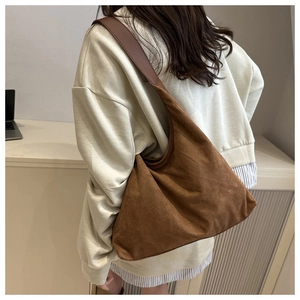 Side view of large brown suede hobo bag worn by model in a minimalist setting