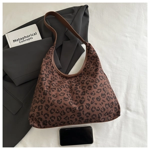 Detail of leopard print tote bag with brown leather strap on a minimalist background