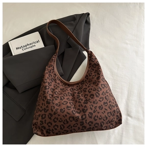 Close-up of leopard print shoulder bag with brown leather straps on aesthetic background