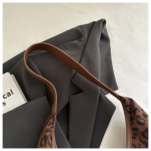 Close-up of stylish leopard print tote bag with brown leather strap and classic patterns