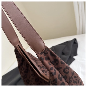 Detail of leopard print tote bag with brown leather strap stitching and soft suede texture