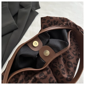 Close-up of leopard print tote bag with magnetic clasp and dark brown leather trim