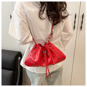 Detailed view of red bucket bag featuring silver rivet studs and a drawstring closure