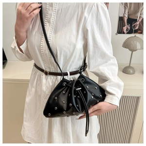 Detail of black drawstring bucket bag with silver studs and polished leather texture