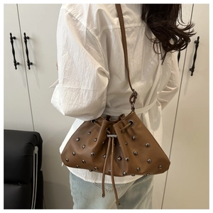 Detail view of a vintage brown drawstring bucket bag with silver metal rivet studs
