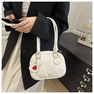 Close-up of white lychee texture handbag featuring a small red heart pendant charm