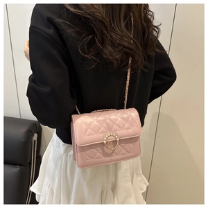 Detail of light pink quilted crossbody bag with pearl buckle and metal chain strap