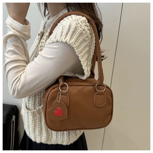 Detail of a brown lychee pattern leather shoulder bag with a cute heart pendant