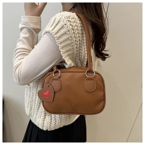 Borsa bowling marrone con trama litchi e ciondolo a cuore indossata a spalla dalla modella