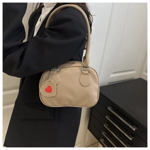 Beige pebble leather handbag with a red heart charm shown in a lifestyle setting