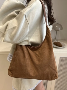 Brown faux suede hobo bag with large capacity shown on model in a minimalist interior
