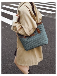 Close-up of quilted rhombic pattern and brown leather straps on the large tote bag