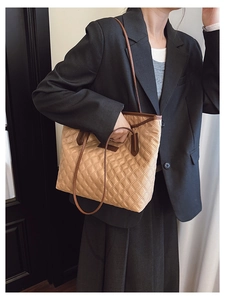Khaki quilted nylon tote bag with brown faux leather straps shown on a model