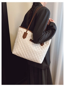 Detail of the diamond quilted pattern and brown leather straps on an ivory tote bag