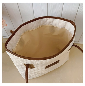 Top view of large white quilted tote bag featuring brown leather trim and spacious interior