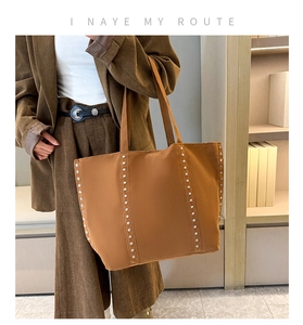 Vue détaillée d'un cabas en daim marron avec rivets métalliques et texture douce élégante