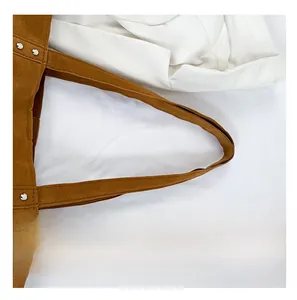 Détail du sac cabas en velours marron montrant la bandoulière large renforcée de rivets