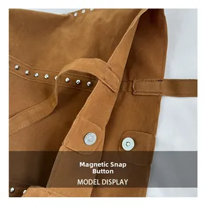 Détail du bouton pression magnétique et des rivets argentés sur le sac en daim marron