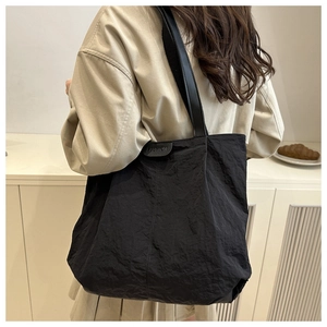 Detail of black pleated tote bag with FASHION label and sleek synthetic leather straps