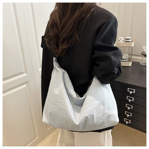Close-up of light blue hobo bag with textured nylon fabric shown in a lifestyle setting