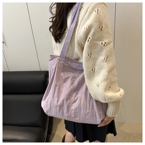 Close-up of lavender nylon tote bag featuring fashion label and wide shoulder strap