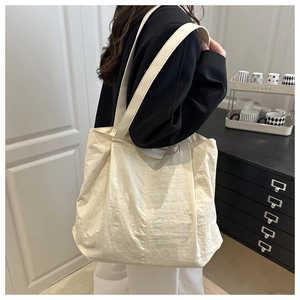 Detail of cream white nylon tote bag showing the fashion label and wide shoulder strap