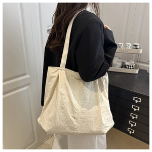 Detailed shot of large beige tote bag with pleated texture and fashion label on shoulder
