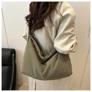 Detail of army green nylon half-moon tote bag with wide shoulder strap on a model