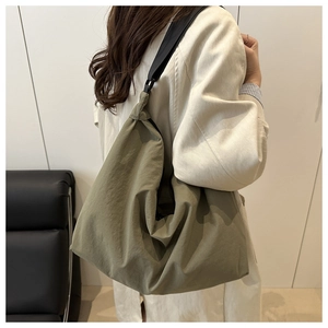 Olive green nylon pillow bag with wide black shoulder strap shown on a model