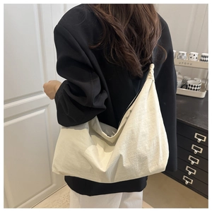 Detail of a large off-white canvas hobo bag showing soft texture on a shoulder strap