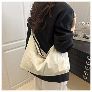 Détails d'un grand sac hobo crème porté par un mannequin dans un décor moderne