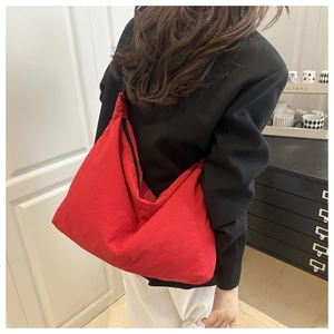 Détail du grand sac besace en nylon rouge avec fermeture éclair noire porté à l'épaule