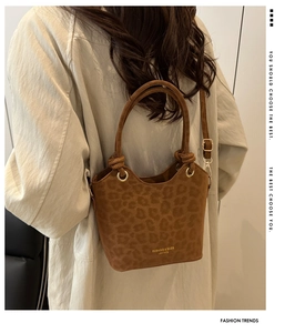 Detail of leopard print bucket bag featuring gold buckle and branding on suede texture