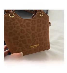 Detailed macro view of leopard print bucket bag with gold lettering and woven strap