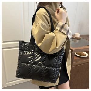 Detailed view of black quilted space cotton tote bag worn over the shoulder in a cozy cafe