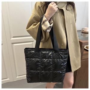 Detail einer schwarzen gesteppten Puffer-Tasche mit Karomuster und breiten Tragegurten