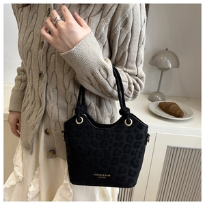 Detail of black leopard print crossbody bag with knotted handle on a beige sweater