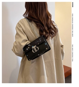 Close-up of shiny black rhinestone crossbody bag with silver chain strap on model