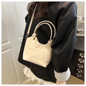 Detail of beige PU leather crossbody bag with gold hardware and embossed logo