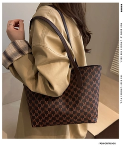 Detail of vintage M letter print tote bag with smooth leather handles on shoulder