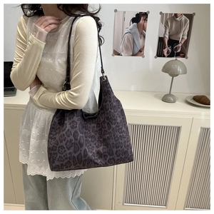 Leopard print hobo bag worn by a model in a cozy interior setting showing large capacity