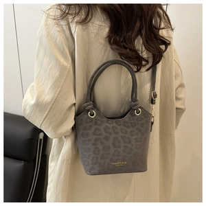 Detail of grey leopard print suede bucket bag with gold lettering and knotted handle