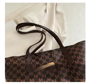 Detail of vintage printed tote bag with leather strap and golden rectangular brand plate