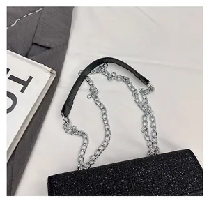Detail of sparkly black crossbody bag with silver chain strap and wide shoulder pad