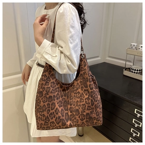 Sac hobo imprimé léopard porté par un mannequin sur une robe blanche chic