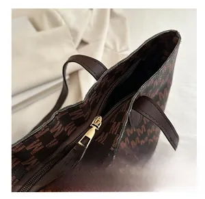 Detail view of smooth golden metal zipper closure on luxury monogram tote bag