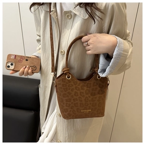Detail of leopard print bucket bag with gold lettering and adjustable shoulder strap