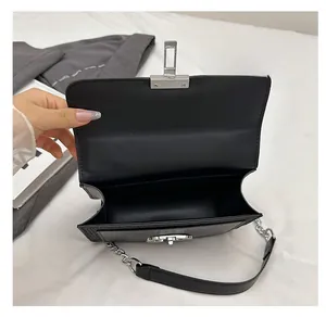 Detail of black leather crossbody bag interior showing spacious compartment and silver clasp