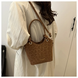 Suede bucket bag with leopard print and golden ring handle worn over the shoulder