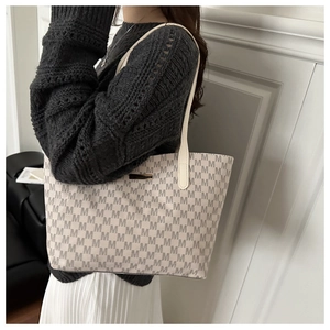 Detail of minimalist tote bag with grey M-letter monogram and golden metal logo plate